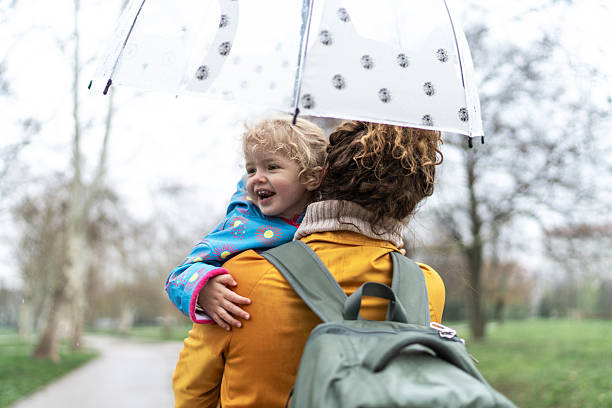 istock Child smiling while being carried by her mother under umbrella 2208679942