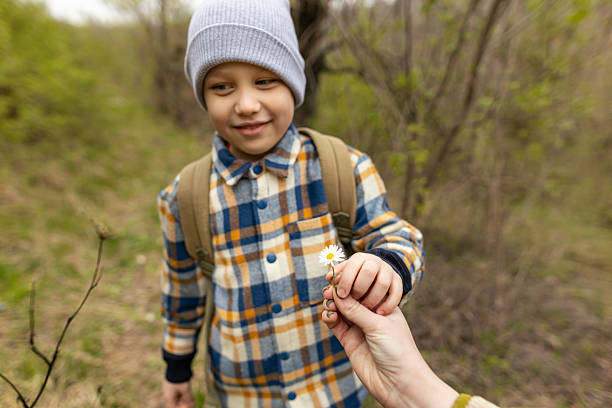 istock Mom give her son a spring white flower 2208680118