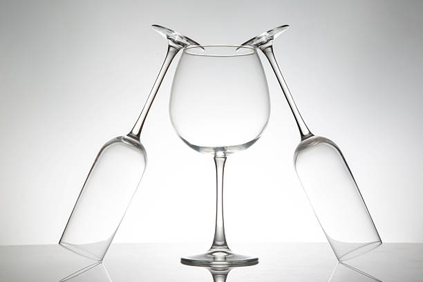 three crystal-clear wine glasses with varied shapes stand in a row, their reflections shimmering on a polished surface, ideal for luxury lifestyle imagery.