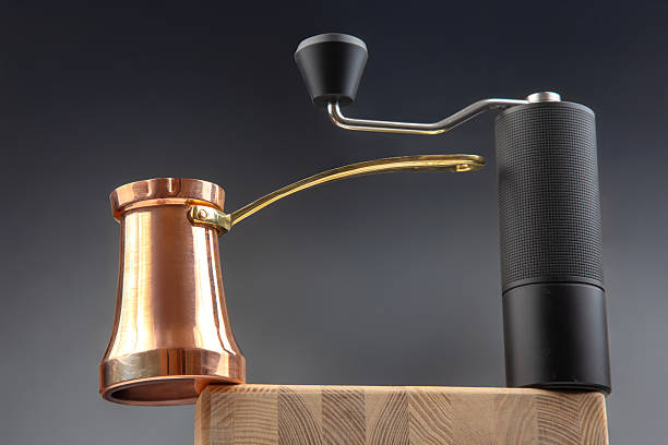 istock a black coffee grinder with a metallic crank beside a copper cezve with a gold handle, great for kitchen stock photos. 2208682770