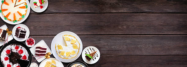 Dessert corner border with a variety of cakes. Above view over a dark wood banner background.
