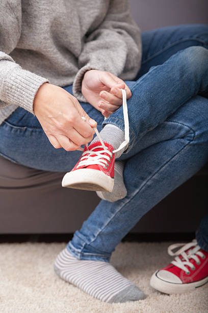 istock Mother untying red sneaker laces – close-up 2208684611