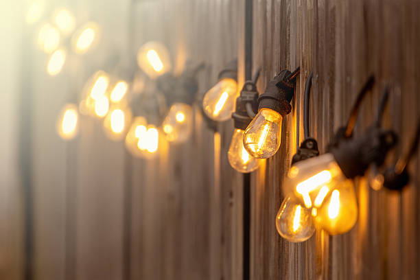 Warm string lights glow softly against a wooden wall, creating a cozy and inviting ambiance