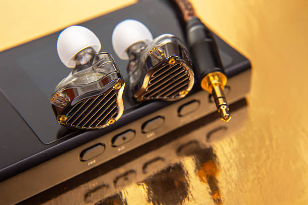 istock Wired earbuds with a woven cable on a black audio device, set on a glossy gold background. Ideal for music lovers, tech enthusiasts, and product shots. High-res photo. 2208685586