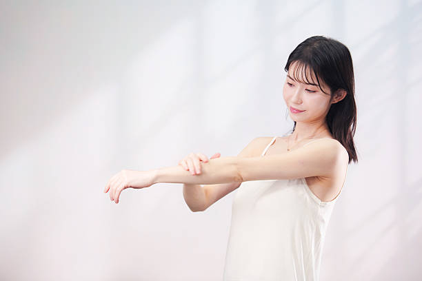 istock Young woman applying cream on arm (simple background) 2208688603