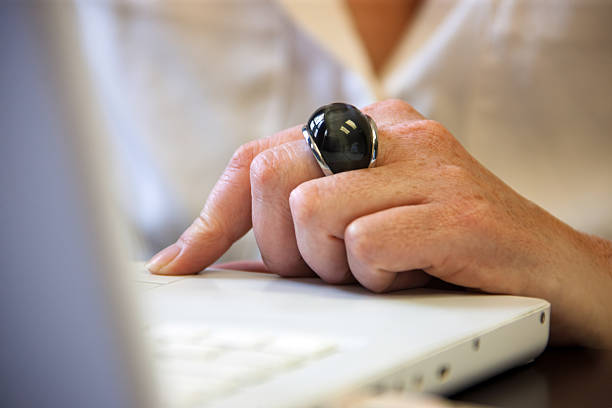 woman hand, using a laptop close-up, gray notebook huge black ring on her finger, white blouse