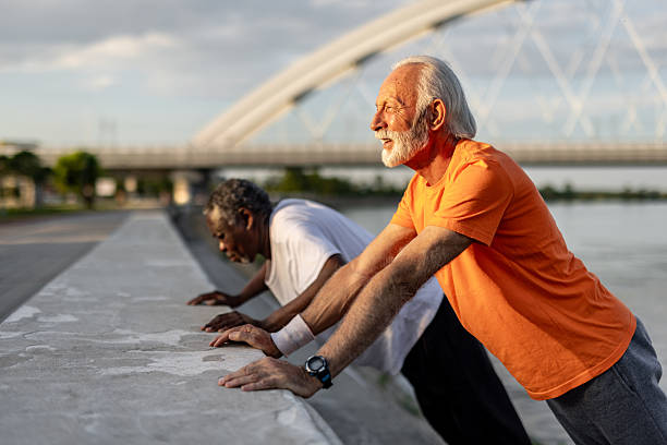 istock Two senior men doing push-ups by the river in the city 2208692601