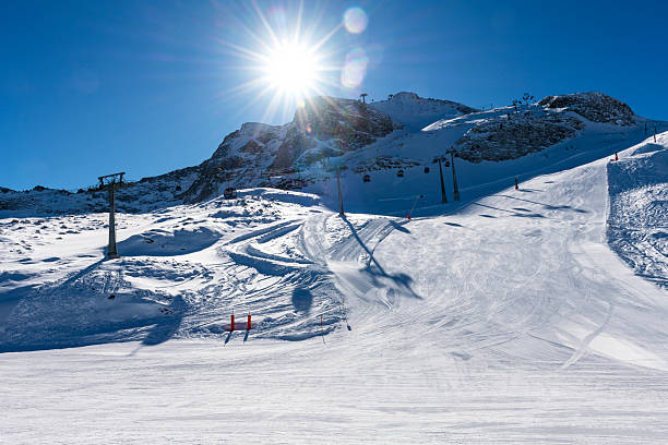 Snowy landscape with ski slope with skiers and snowboarders at Swiss mountain resort of Flumserberg on a late winter day. Photo taken March 16th, 2025, Flumserberg, Switzerland.