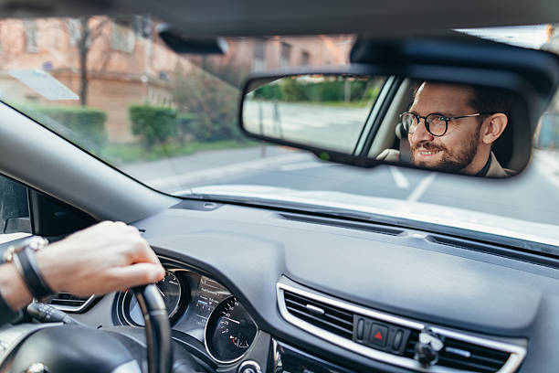 Businessman driving car and looking at rearview mirror