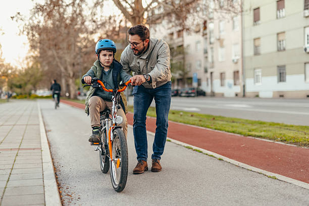 istock Father teaching son how to ride bicycle in the city 2208700125