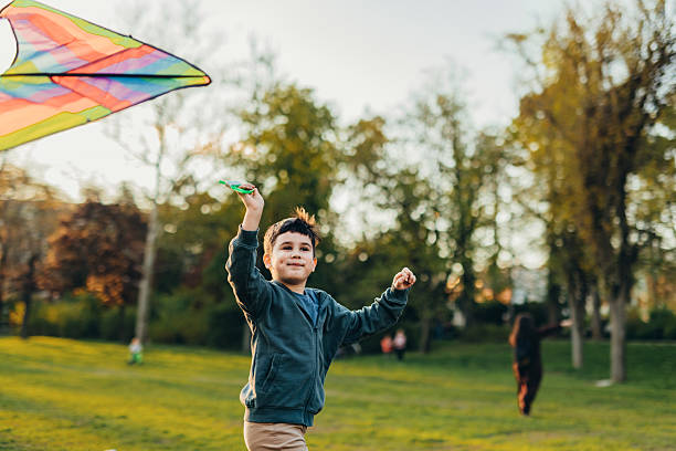 istock Happy child playing with kite in park during sunset 2208700488