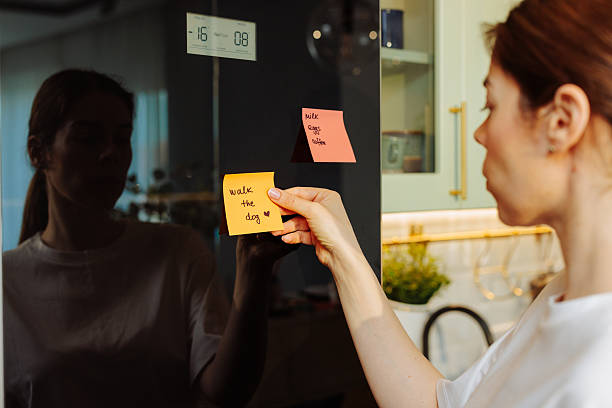 istock Woman sticking a reminder note on the refrigerator door 2208704024