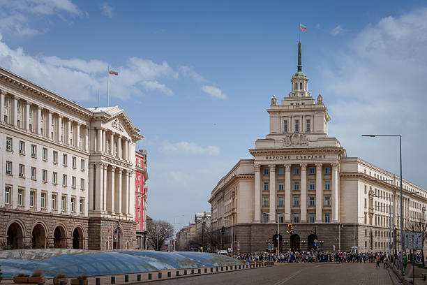 A wide view of the National Assembly building in Sofia, Bulgaria, under a partly cloudy sky.