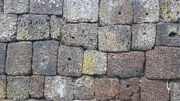 Old brick wall background, ancient castle stone wall in Thailand, fence made of large stones stacked in layers, ancient construction.