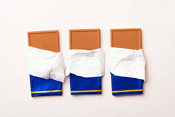 Stock photo showing close-up, elevated view of an assortment of luxury collection of Belgian chocolate biscuits, pictured against a mottled blue background.