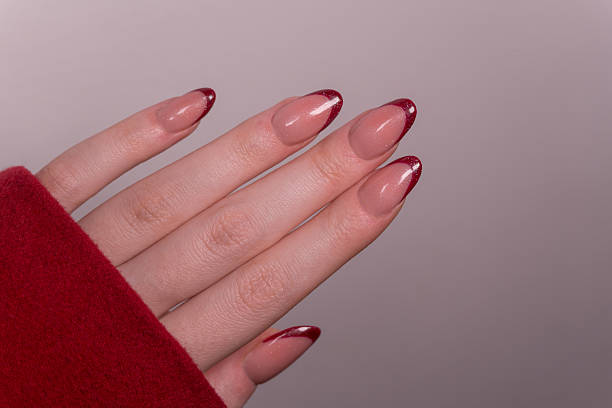 istock Glossy red French manicure – Smooth, shiny tips highlight well-groomed hands and make a bold statement. Well-groomed hand with glossy red-tipped nails in an elegant French manicure style. 2208710484