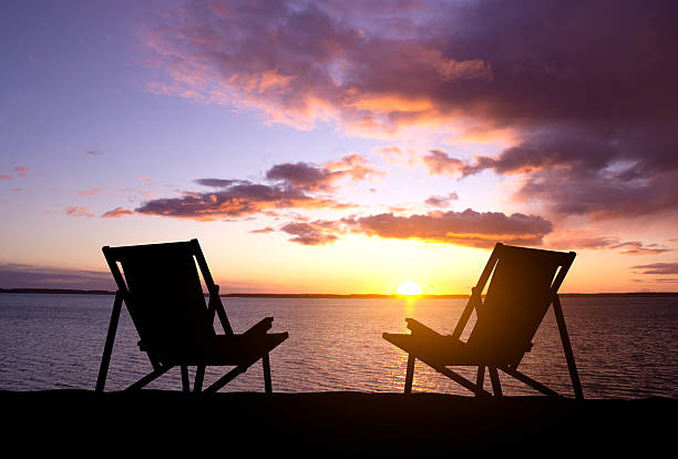 Silhouette of a deck chairs on the beach against the sunset. Summer vacation concept