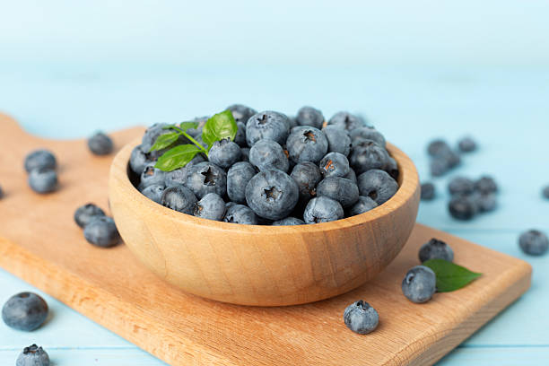 istock Bowl with fresh bright blueberries on wooden table 2208715627