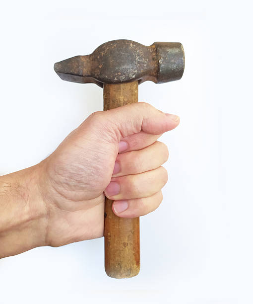 istock Hand holding a rustic hammer against a clean white background. Symbolizes construction, repair, or determination. Ideal for DIY, home improvement, and strength concepts. 2208726046