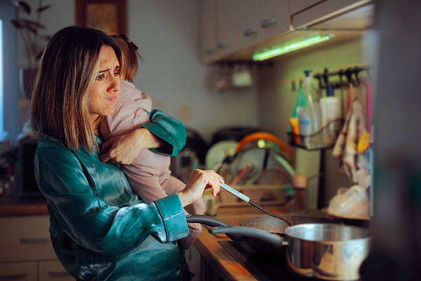istock Busy Mom Holds Baby While Preparing Meal in Kitchen 2208726833
