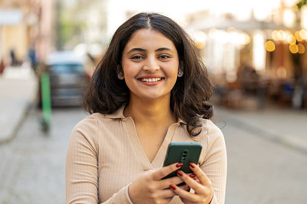 istock Indian woman use smartphone typing text messages browsing internet finishing work looking at camera 2208733715