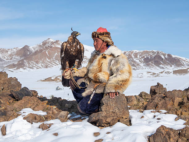 Ulgii, Mongolia - September, 30, 2023: Portrait of a male hunter with a hunting golden eagle. Eagle hunters are individuals who train and hunt with golden eagles in Northern Mongolia.
