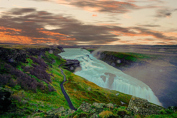 istock Gullfoss, one of Icelandmost iconic waterfalls, thunders through rugged terrain, offering visitors a mesmerizing view of cascading torrents framed by vibrant green landscapes and dramatic skies. 2208735286