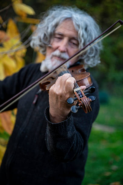 istock Elderly man with grey hair playing a violing outside 2208735566