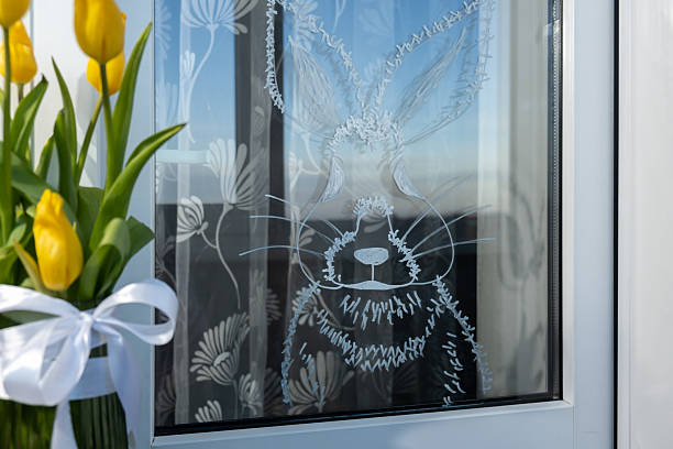 Zero cost responsible holiday decor economically driven. Painted Easter bunny rabbit on window glass indoor at home. Affordable alternative Easter springtime seasonal tradition ideas decoration. Diy cost-saving