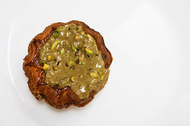 close up of pistachio flower shape cream tart on a white plate isolated background with copy space