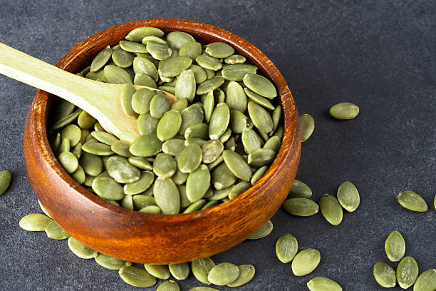 istock Delicious pumpkin seeds on black background 2208759978