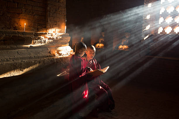 istock Two young Buddhist monks pray in a mystical atmosphere inside an ancient temple 2208764257