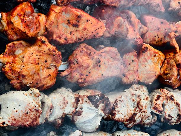 Burnt pork skewers on iron grill, outdoors, close-up, over real charcoal, selective focus. High quality photo
