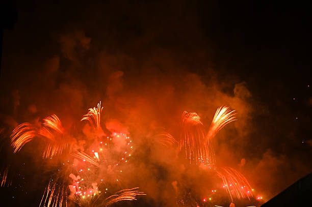 Stunning and colorful fireworks display in the night sky with smoke during explosion. Real fireworks background. Abstract of real shining fireworks against black background. for celebration.