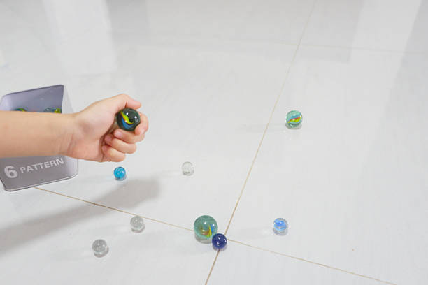 Close up boy hands plays flipping marble balls with fingers. Concept. object use as toy for playing games for fun or competition. Traditional game, use marble ball as equipment.