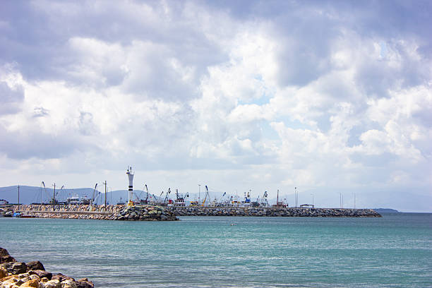 Ship port with a small light house on a calm sea with rain clouds.