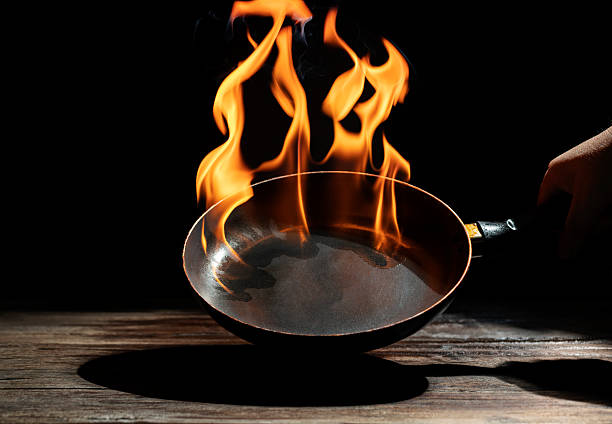 istock Black cooking pan with flames placed in kitchen on dark background table. 2208785421