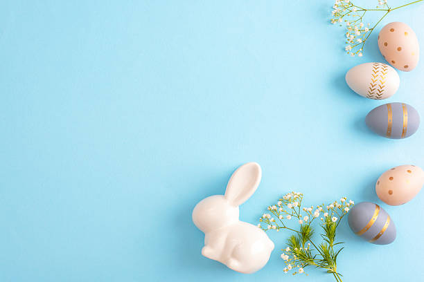 istock White ceramic bunny with pastel decorated easter eggs and flowers on blue background. Easter holiday concept. Top view, flat lay, copy space 2208786594