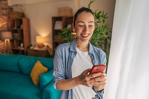 istock Young woman using mobile phone and smiling at home 2208792464