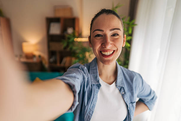 istock Young woman taking a selfie at home, smiling at the camera 2208792532