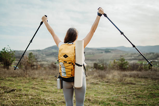 istock Young woman hike or trek and explore scenic forest with hiking sticks 2208793219