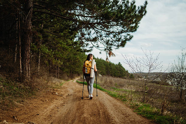 istock Young woman hike or trek and explore scenic forest with hiking sticks 2208793231