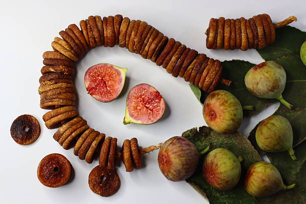 Dried and fresh figs on a white background, highlighting their color and texture. Rich in fiber, antioxidants, and minerals, they aid digestion and wellness. Ideal for food blogs and magazines