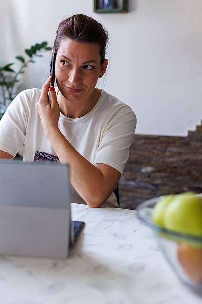 istock Woman Talking on the Phone While Working from Home on Laptop 2208793537