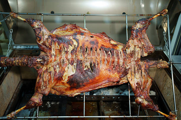 Lamb on a spit Greek style, Whole lamb on a rotisserie spit, Open fire Spit Roasting Lamb for Greek Easter