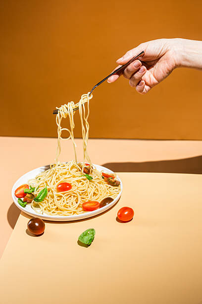 istock Spaghetti with tomatoes and basil in a plate on a yellow background 2208795505