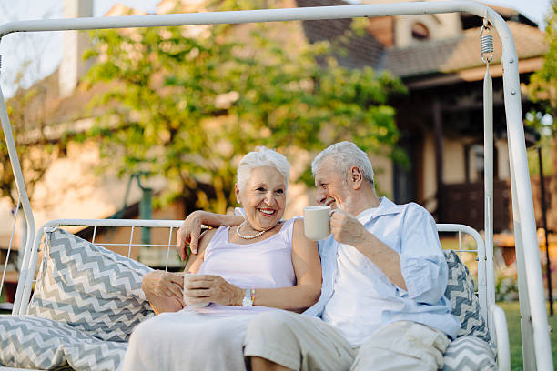 istock An elderly couple drinks coffee while swinging on a swing in the backyard 2208798977