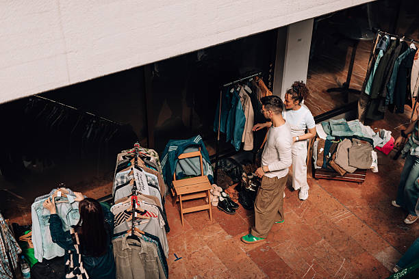 Shoppers browsing through a vibrant outdoor flea market, selecting pre-owned garments while searching for unique and affordable fashion treasures among various stalls
