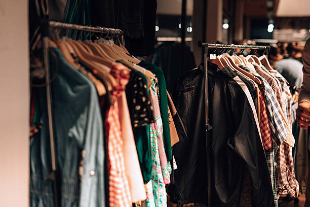 Interior of a modern clothing store with organized shelves of folded sweaters and a customer selecting a white t-shirt