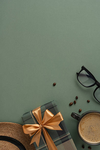 istock Vertical flat lay with a wrapped gift, coffee, glasses, and hat on a green surface creating a cozy atmosphere 2208807170
